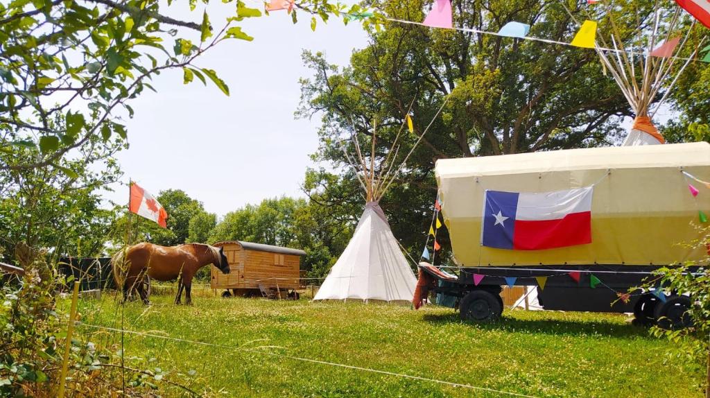 a horse standing next to a trailer and a tent at Clos de l'Isop, le village d'hébergements insolites in Saint-Martial-sur-Isop
