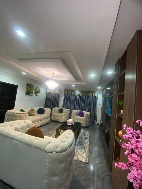 a living room with white couches and a tv at Luxury 2 Bedroom Apartment in Magodo