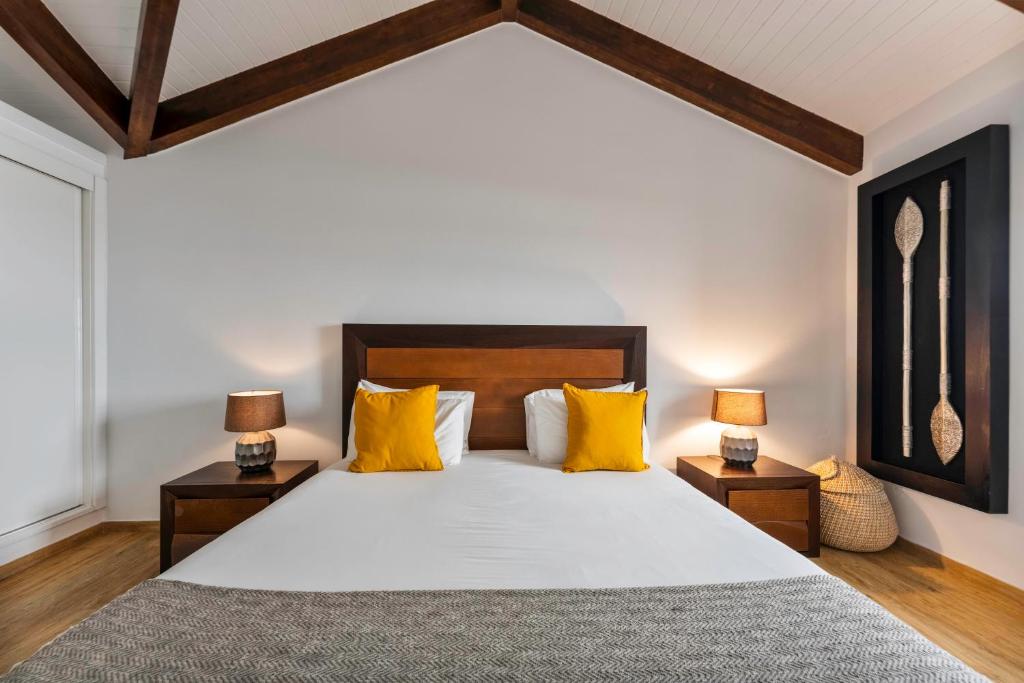 a bedroom with a large bed with yellow pillows at Kuanza Nature Experience, Fajã do Belo in Fajã da Caldeira de Santo Cristo