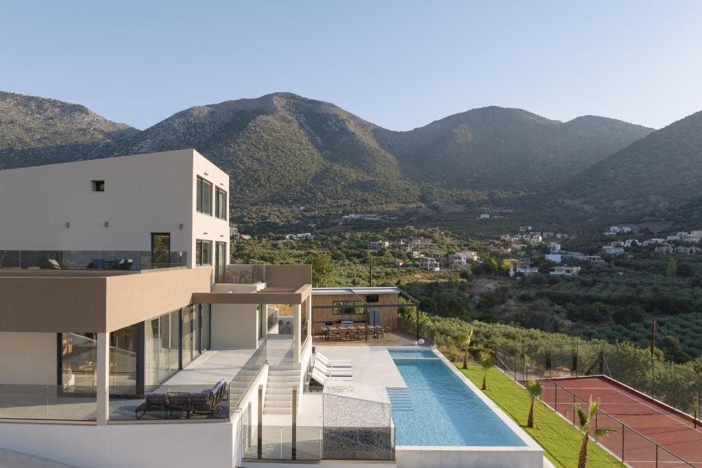 a house with a swimming pool and mountains in the background at Dias Villa, Tennis, 2Pools, Walk to Beach & Shops, By ThinkVilla in Vlikhádha