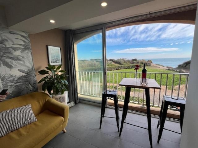 - un salon avec un canapé, une table et une grande fenêtre dans l'établissement Vue mer au bord des falaises, au Cap d'Agde