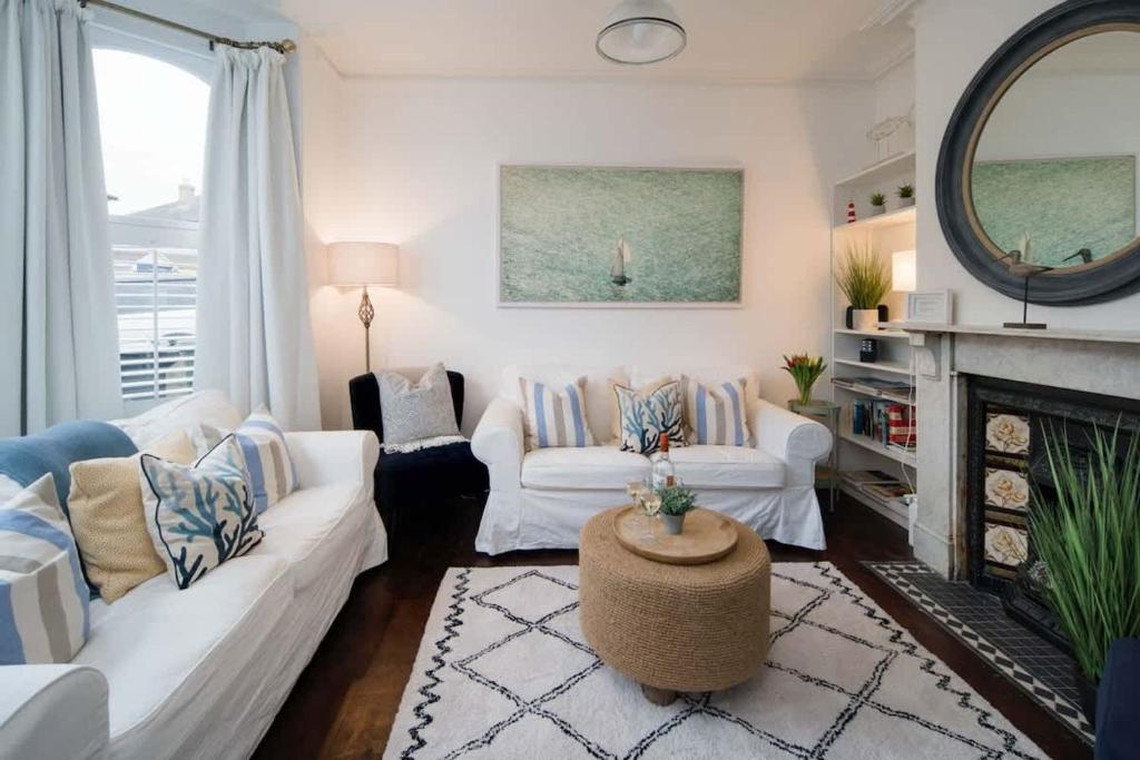 een woonkamer met 2 witte banken en een open haard bij Firefly House in Cowes