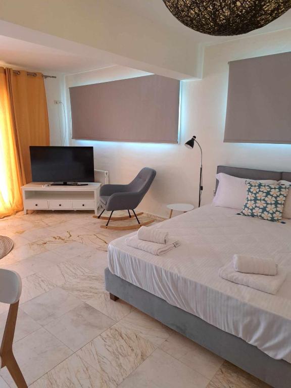 a bedroom with a bed and a tv and a chair at Modern apartment in Paleo Tsifliki