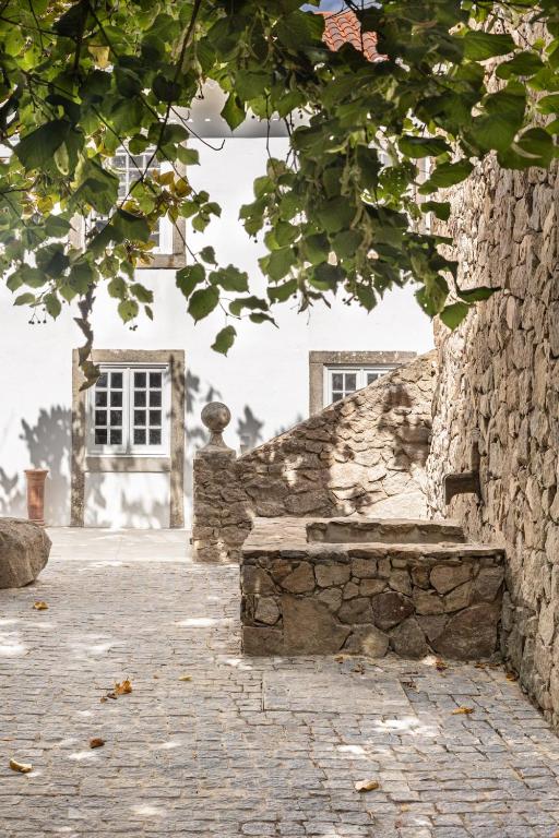 a stone wall with a stone bench in front of a building at QG - stop in Colares