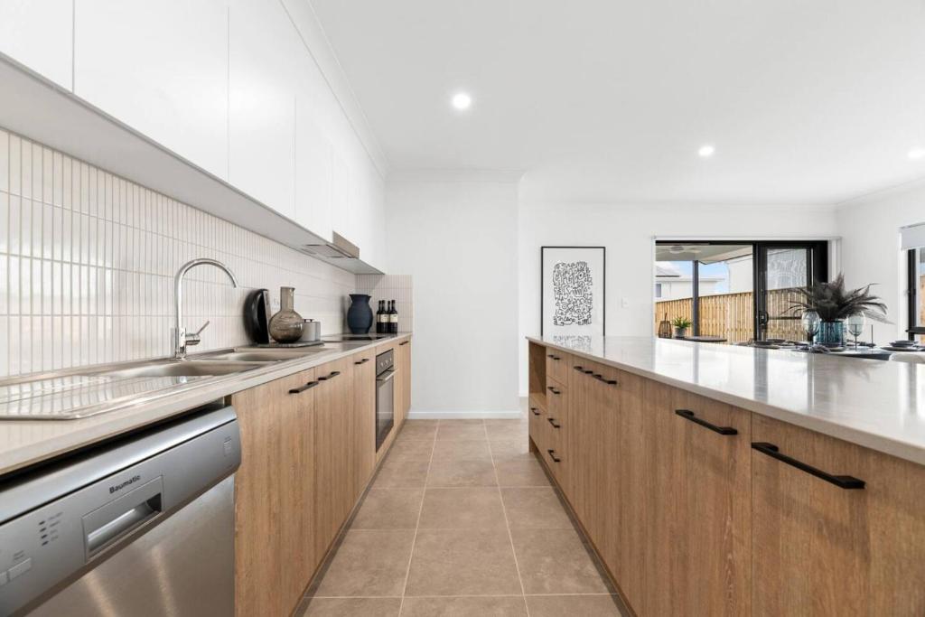 a kitchen with wooden cabinets and a sink at Noble Casa Brand New Estate Sleeps 8 Burpengary East in Morayfield