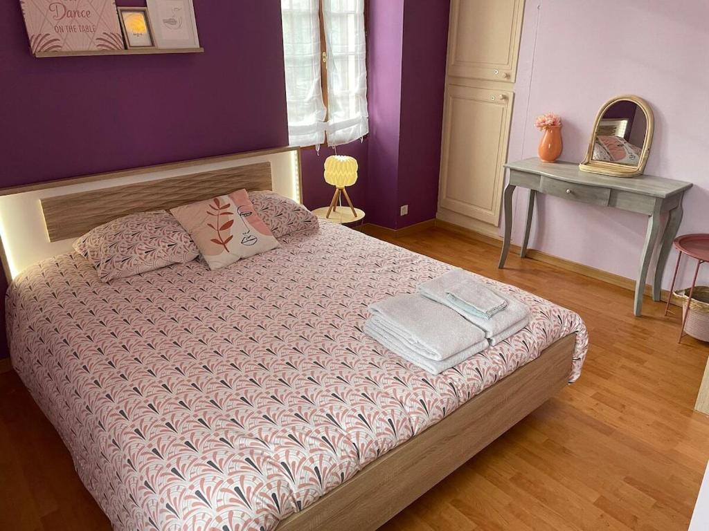 Schlafzimmer mit einem Bett mit lila Wänden und einem Tisch in der Unterkunft Maison de ville avec parking gratuit in Chablis