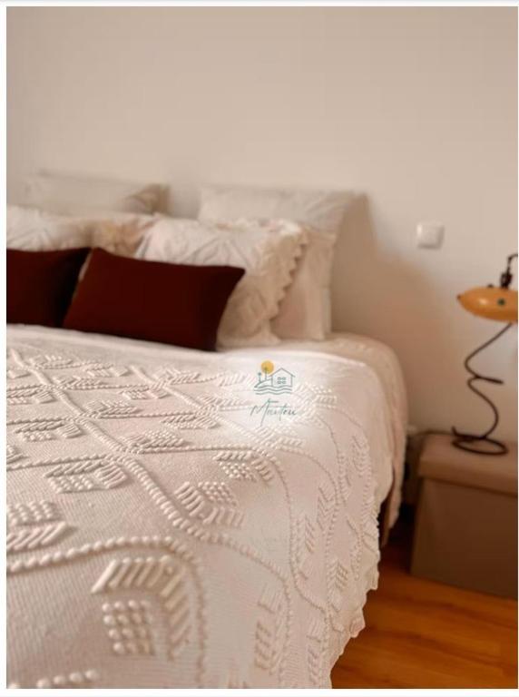 a white bed with a white comforter and pillows at Casa MarTeu in Pêra