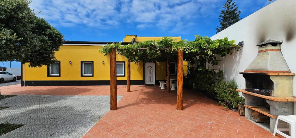 a yellow and white building with a courtyard with trees at Santa Barbara Beach hotspot in Ribeira Grande