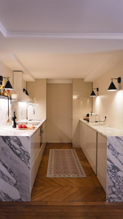 - une cuisine avec des comptoirs blancs et un évier dans l'établissement VENDOME Parisian elegance with a patio, à Paris