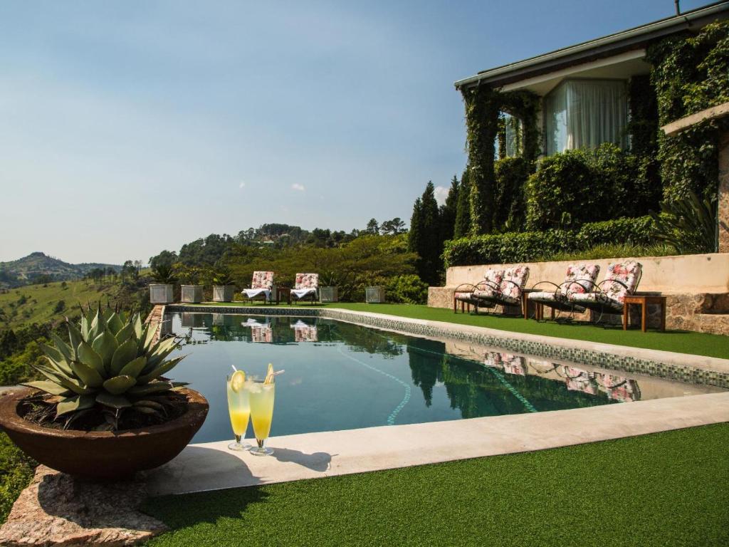 a pool with two drinks sitting next to a house at Ematjeni Retreat & Guesthouse in Mbabane