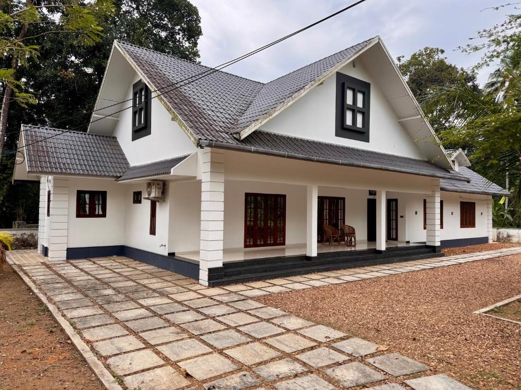 a white house with a black roof at Cheers Home Stay in Pala