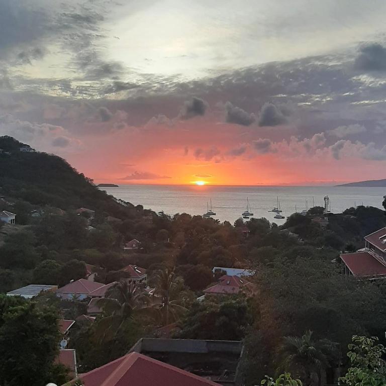 a sunset over a city with boats in the water at Chez Pascal in Terre-de-Haut