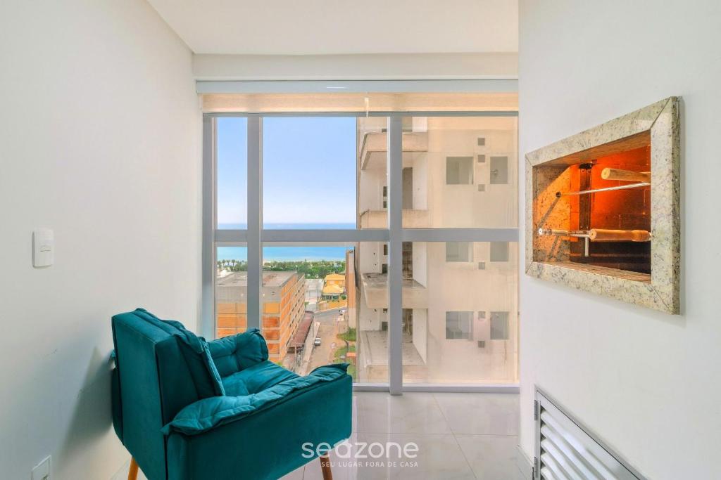 a blue chair in a room with a large window at Apto com vista incrível a 230m do Mar - MRE1101 in Perequê