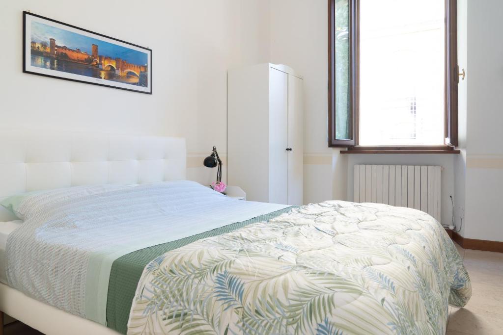a white bedroom with a bed with a blanket at Ponte Nuovo BB in Verona