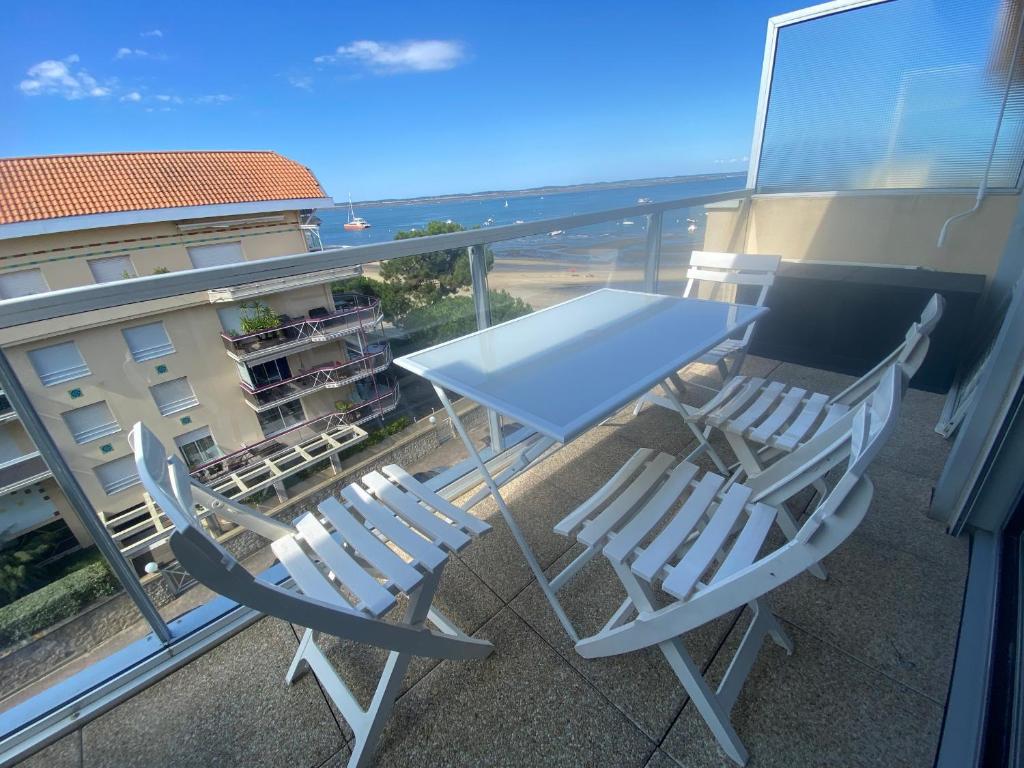 une table et des chaises sur un balcon avec vue sur un immeuble dans l'établissement Appartement T1 avec Terrasse et Parking Sécurisé - FR-1-374-234, à Arcachon