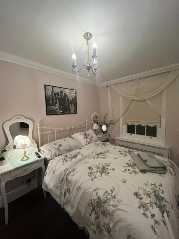 ein Schlafzimmer mit einem Bett und einem Tisch mit einer Lampe in der Unterkunft Cluaine Meala cottage in Isleworth