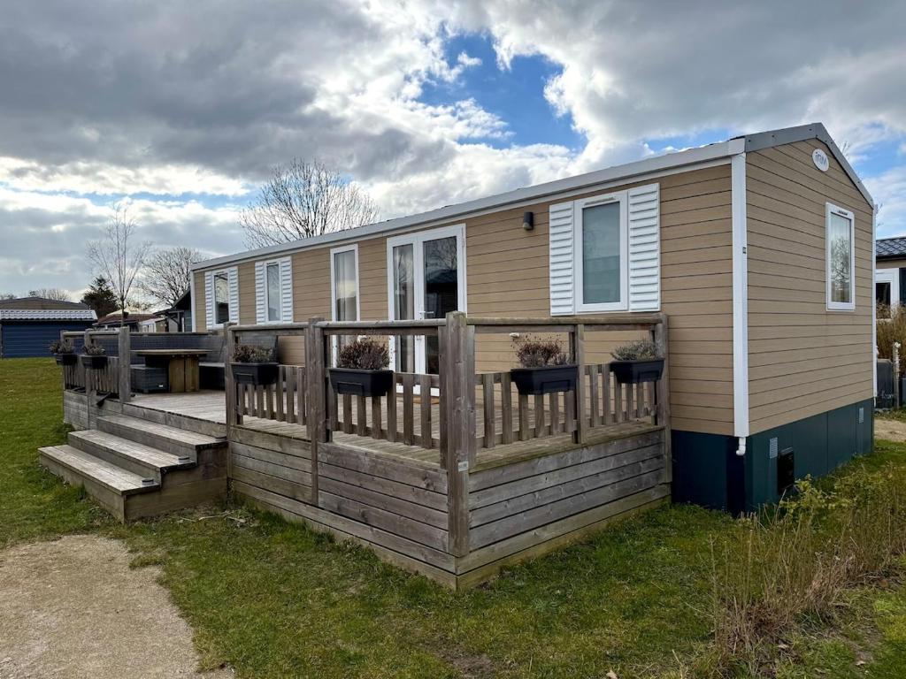 a tiny house with a porch and a deck at Gemütliches Chalet in Strandnähe in Oostkapelle