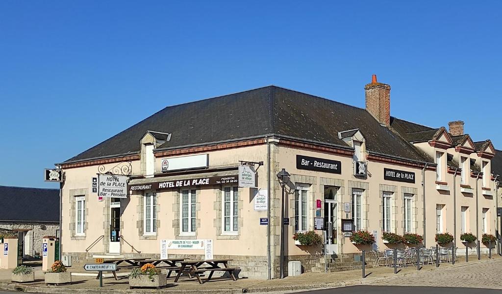 a building on a street with benches in front of it at Hôtel de la Place in Germigny-des-Prés