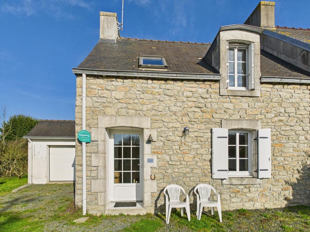 une maison en pierre avec deux chaises devant elle dans l'établissement Agréable maison avec grand jardin pour 4, à Saint-Jean-Trolimon