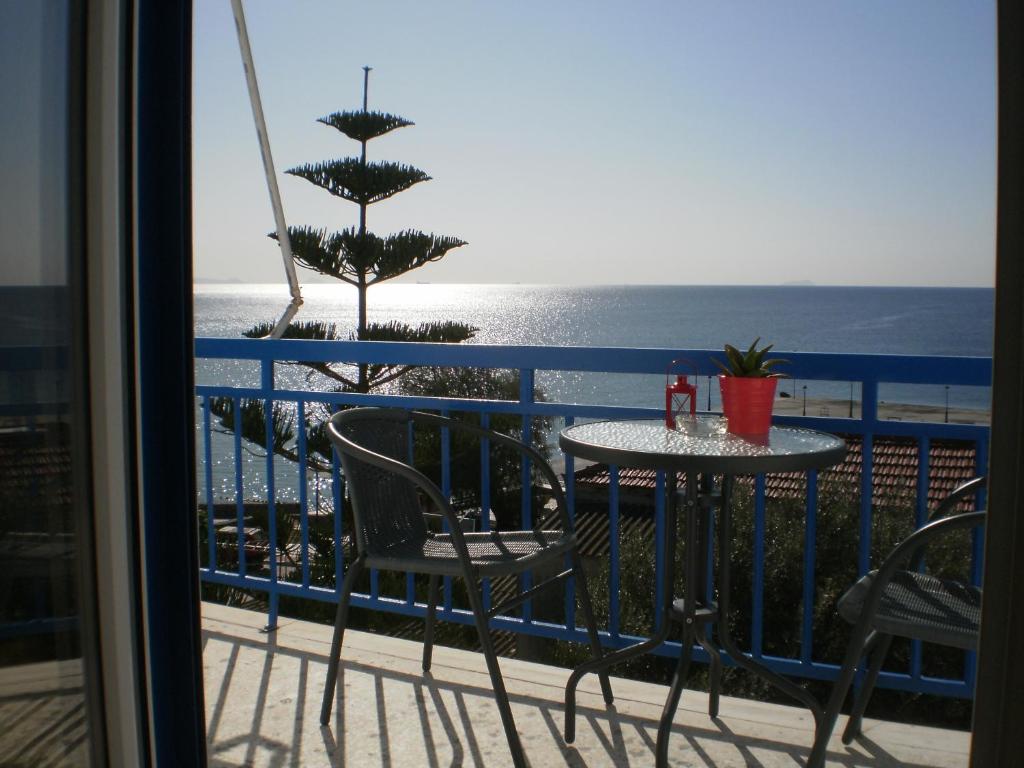 a balcony with a table and chairs and the ocean at Sunrise Flora in Agia Marina Aegina