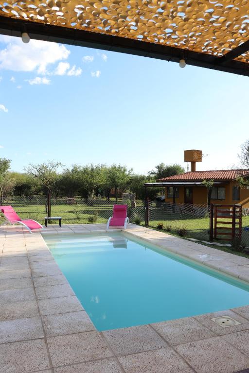 een zwembad met twee stoelen en een huis bij Arawi Cabaña in Merlo