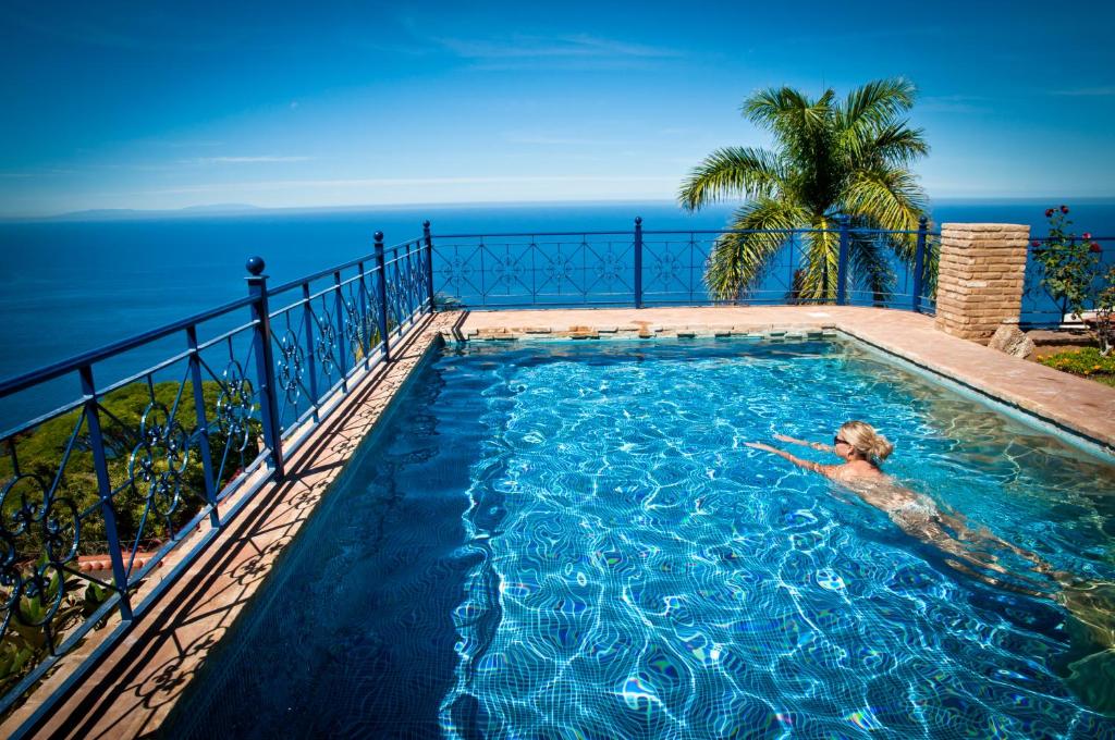 een man in een zwembad met uitzicht op de oceaan bij Villa Casa del Sol in La Matanza de Acentejo