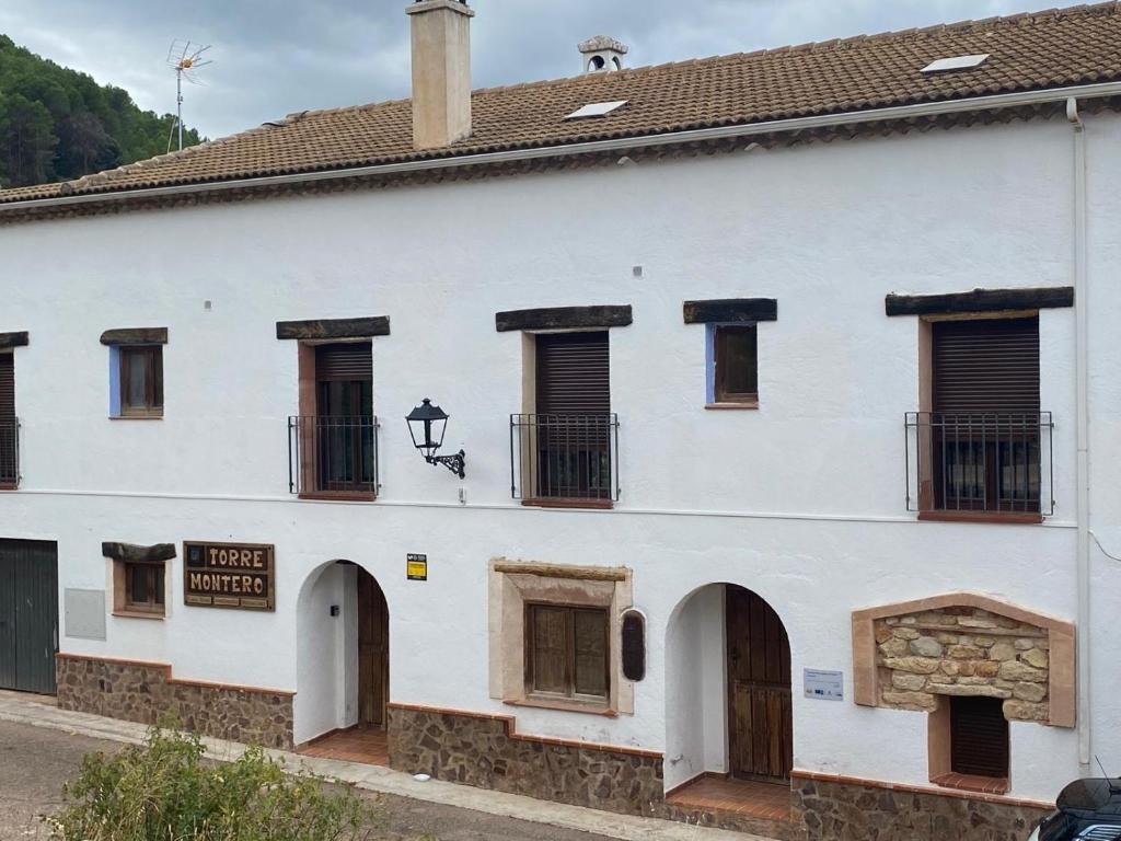 a white building with windows and a sign on it at Casa Rural TorreMontero Apartamentos in Hornos el Viejo