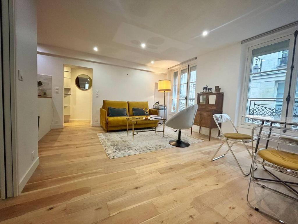 un salon avec un canapé jaune et une table dans l'établissement Parisian Chic Near Opera Louvre, à Paris