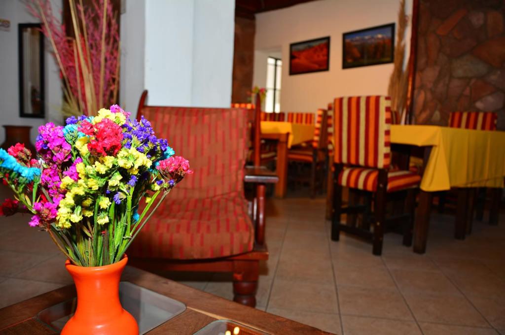 un jarrón naranja lleno de flores de colores en una mesa en Hotel La Giralda en Salta