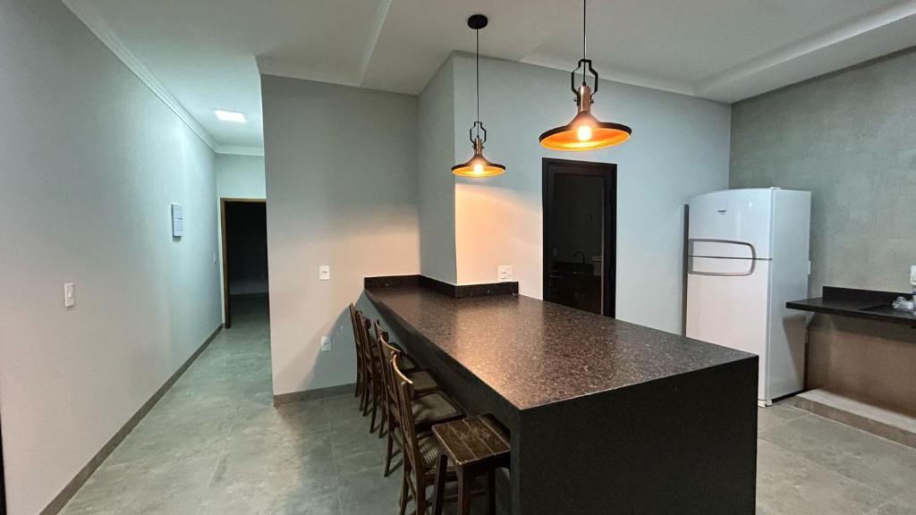 a kitchen with a black counter and a refrigerator at Casa Europa Barretos in Barretos