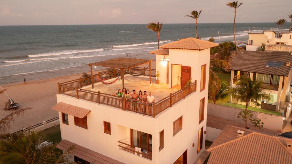 un grupo de personas de pie en el balcón de una casa cerca de la playa en Villa Continentes Brasil & Maison de rêve sur la plage, en Guajirú