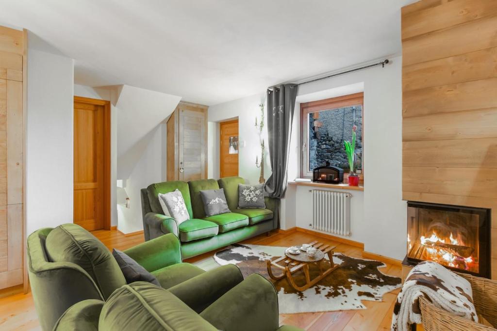 a living room with a green couch and a fireplace at Maison Villarisson Chalet di Charme La Salle a due passi dal Monte Bianco in Remondey