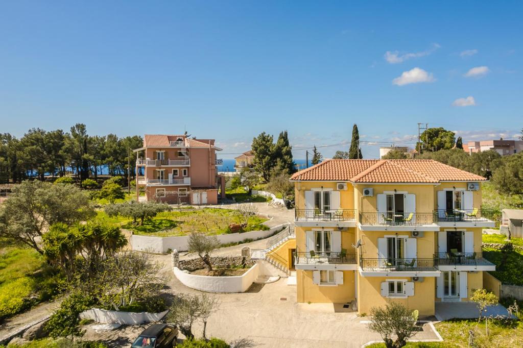a yellow house with a garden in a city at Kallithea Studios & Apartments in Lakíthra