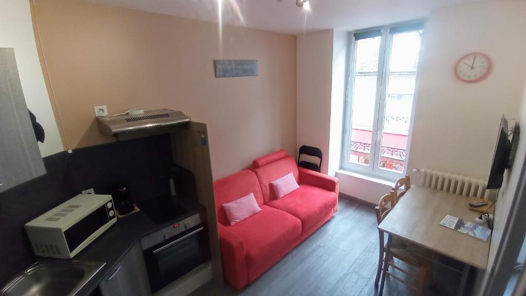 - un salon avec un canapé rouge et une fenêtre dans l'établissement Les Champs d'Auvergne, à Le Mont-Dore