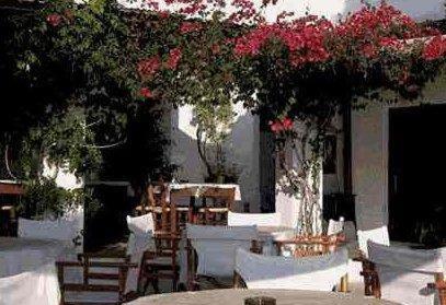 a patio with tables and chairs and pink flowers at Agistri Club Hotel in Skliri