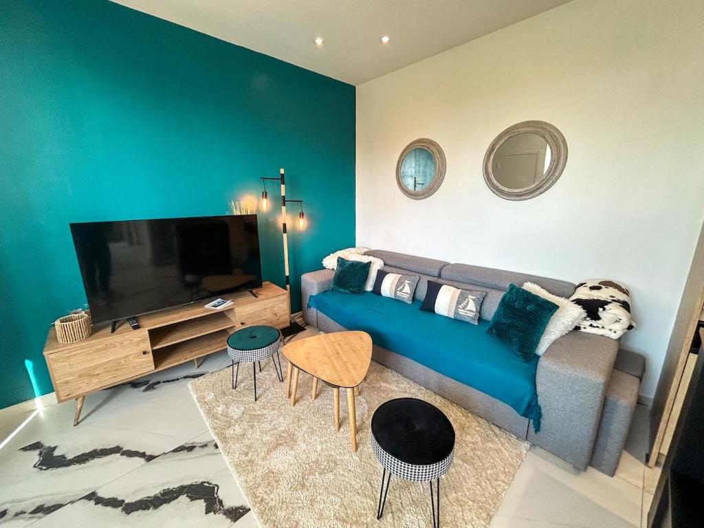 un salon avec un canapé bleu et une télévision à écran plat dans l'établissement L'Escale Cancalaise maison 6 personnes, à Cancale