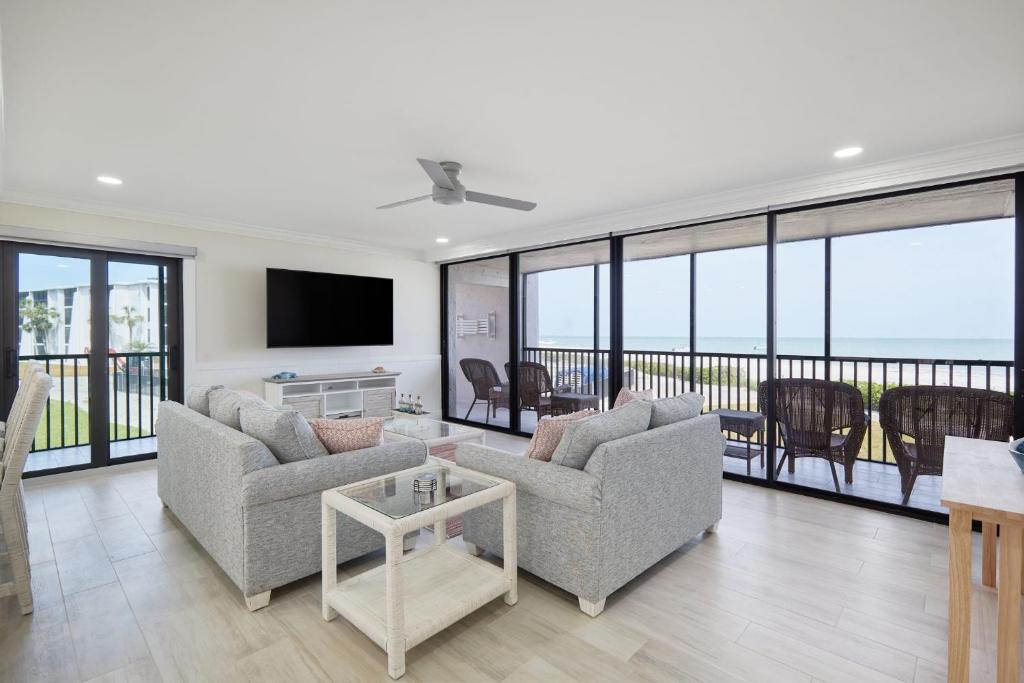 a living room with two couches and a television at Sundial A201- Gorgeous Beachfront Condo at Sundial in Sanibel