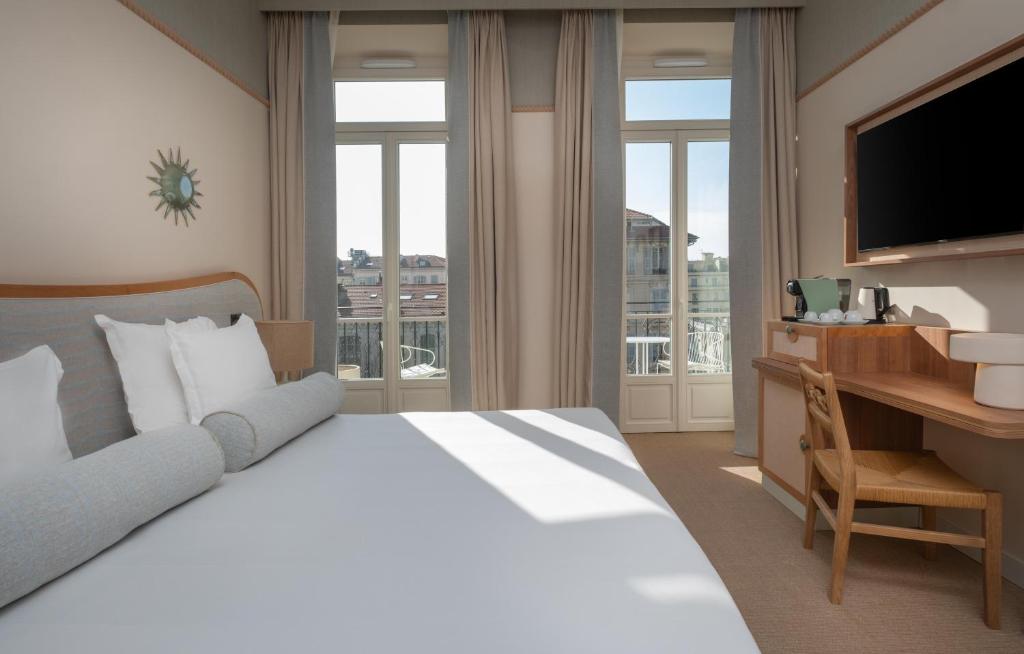 een slaapkamer met een bed, een bureau en een televisie bij Hôtel Le Soleia by Inwood Hotels in Nice
