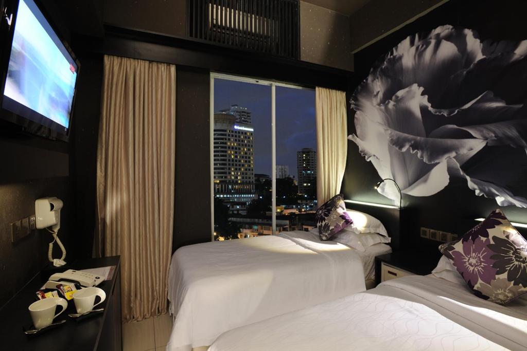 クアラルンプールにあるル アップル ブティック ホテル ブキット ビンタンのベッド2台と大きな窓が備わるホテルルームです。
