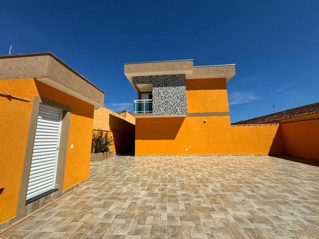 une grande maison orange avec une allée carrelée dans l'établissement Casa Raio de Luz, à Itanhaém