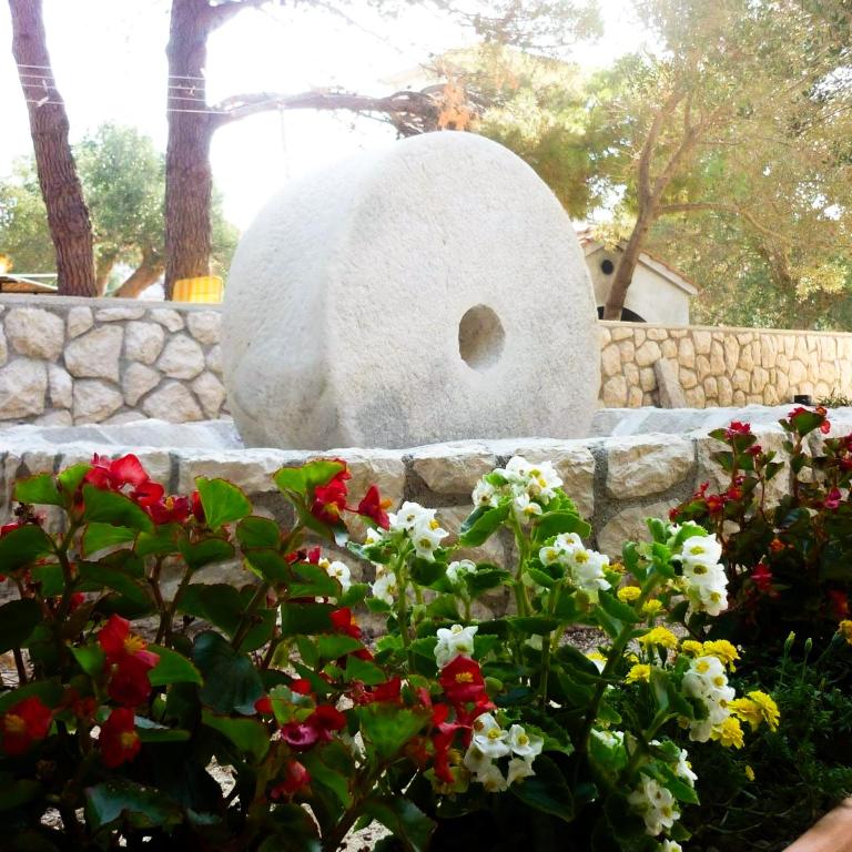 a stone bird bath in a garden with flowers at apartman MLIN 4 in Lun