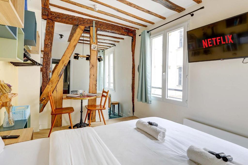 une chambre avec un lit et une table avec des chaises dans l'établissement Sejour Parisien Elegant pour 2 Personnes, à Paris