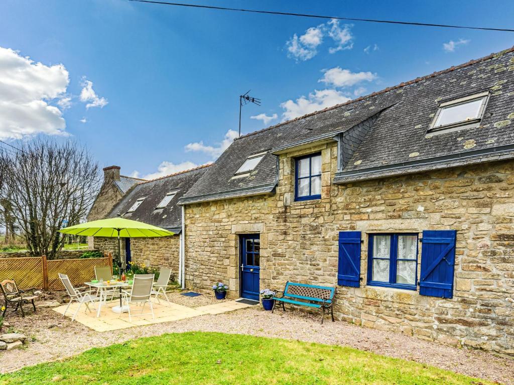 une maison en pierre avec une table, des chaises et un parasol dans l'établissement Holiday Home Maison de Kerguen by Interhome, à Ploemeur