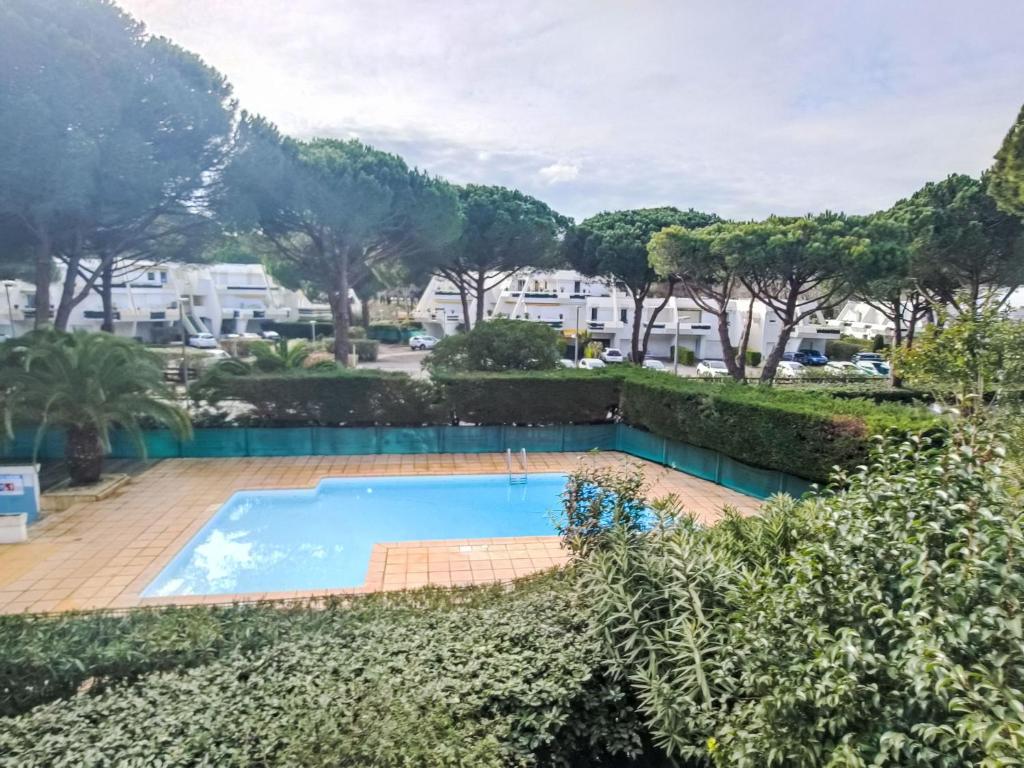 une piscine dans un jardin avec des arbres et des bâtiments dans l'établissement Apartment Les Villégiales Tee1 by Interhome, à La Grande Motte
