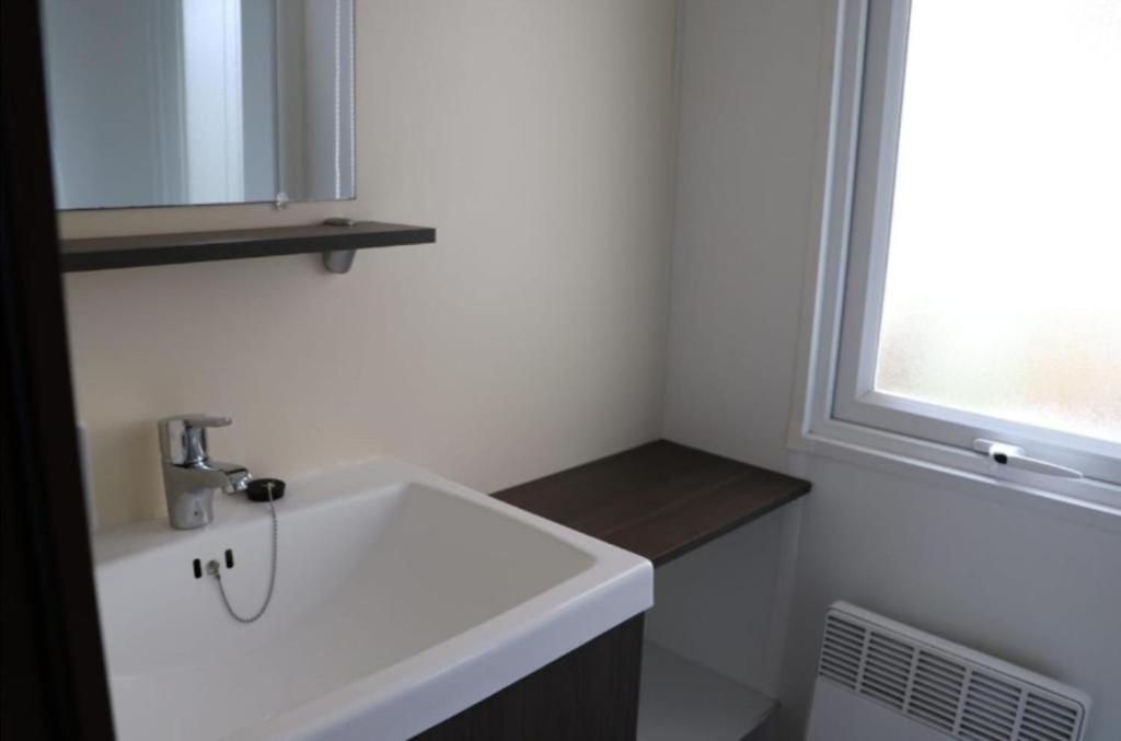 une salle de bain avec un lavabo blanc et une fenêtre dans l'établissement MH 395 3 chambres et 1 salle de bain dans camping 4 étoiles, à Saint-Julien-en-Born