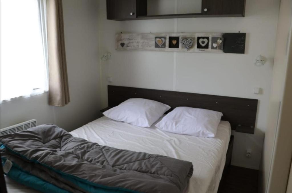 une petite chambre avec un lit avec deux oreillers dans l'établissement MH 395 3 chambres et 1 salle de bain dans camping 4 étoiles, à Saint-Julien-en-Born