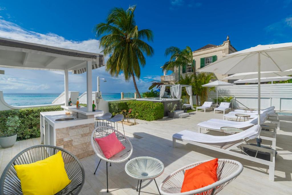 a patio with chairs and umbrellas and the ocean at Solaris Beach House - Beachfront Property, St James in Saint James
