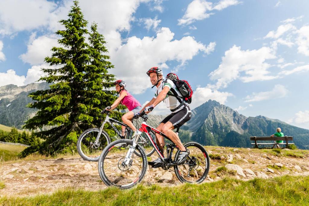 dwoje ludzi jeżdżących rowerami na wzgórzu w górach w obiekcie Zimmervermietung Gröberhof w mieście Schenna