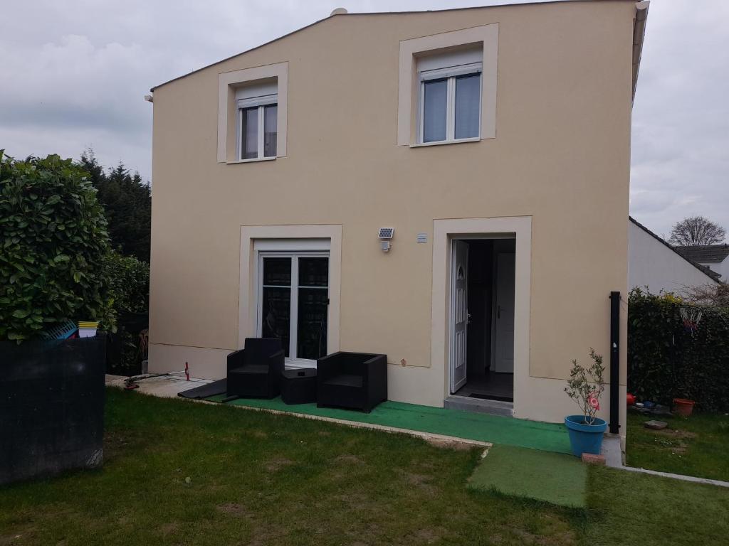 a white house with two black chairs in the yard at Family House in Beauvais
