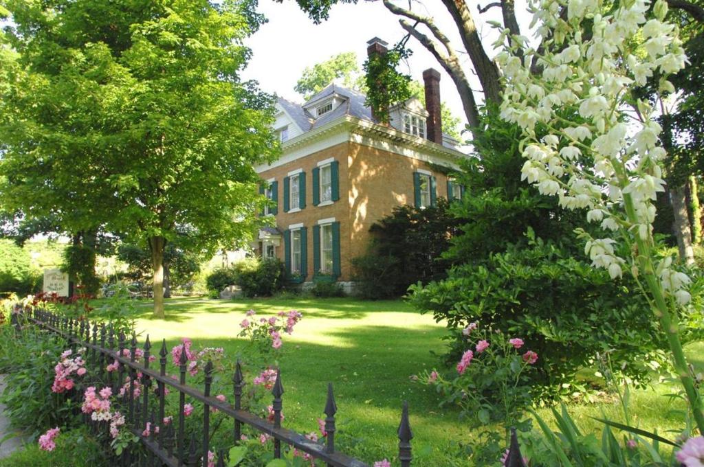a house with a fence and flowers in the yard at Historic Manor Overlooking Park in Bloomington